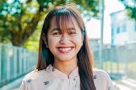 Joyful young woman smiling brightly outdoors on a sunny day.